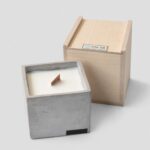 Oscar Outdoor Kubus Kaars M 11x11cm betonnen buitenkaars met houten wiek naast houten geschenkdoos