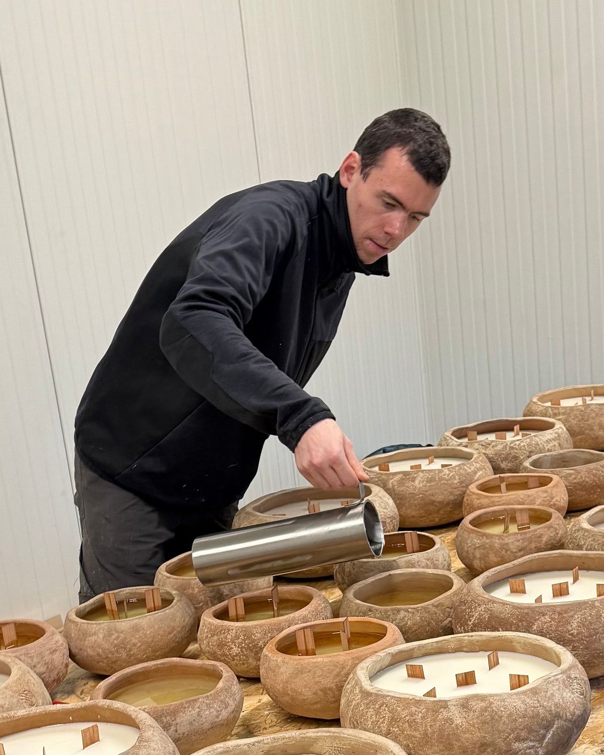 Candle maker pouring wax into outdoor candles at the Oscar Luxury atelier in Brecht